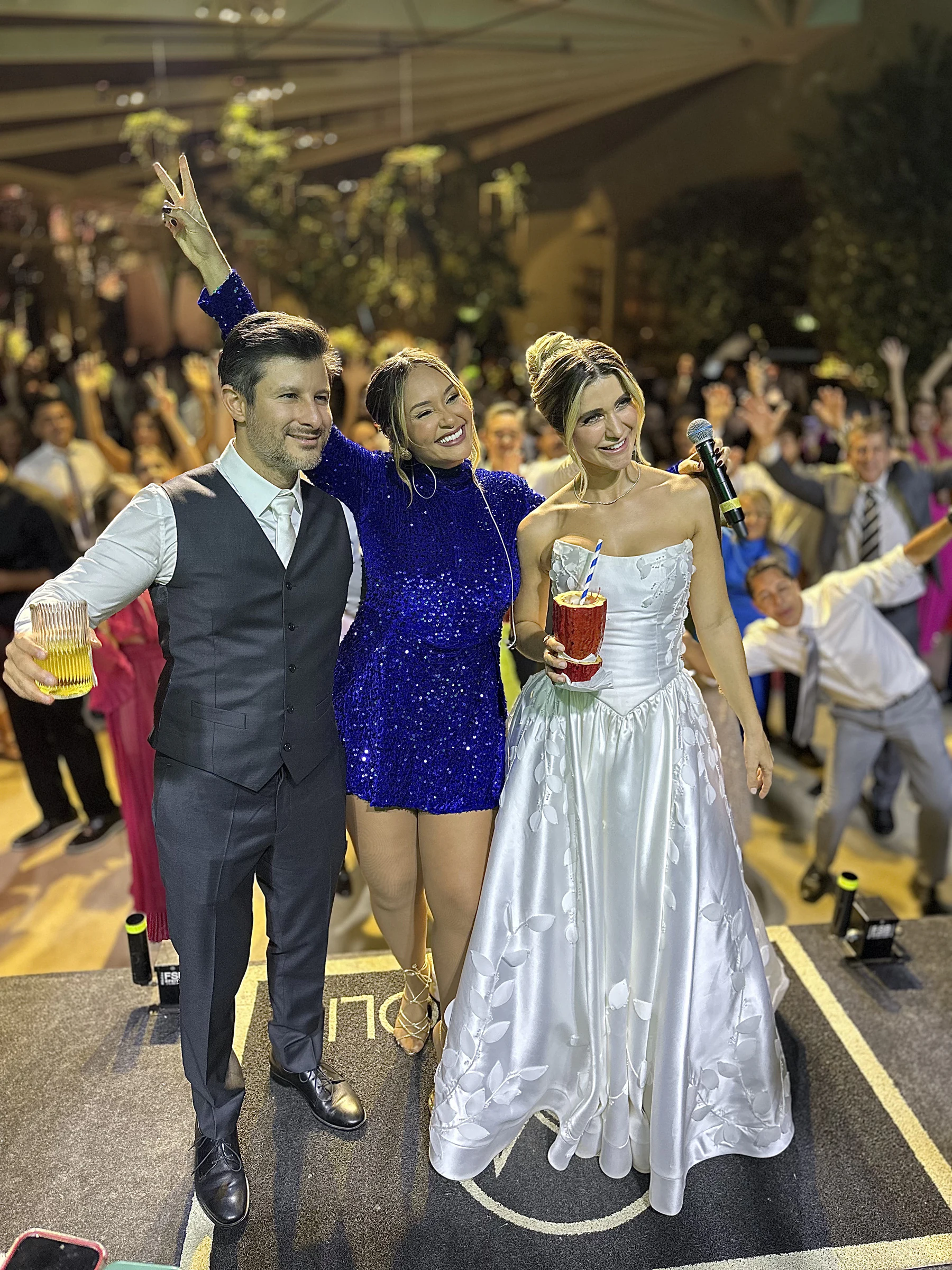Tainá entre os noivos em meio aos convidados durante a celebração