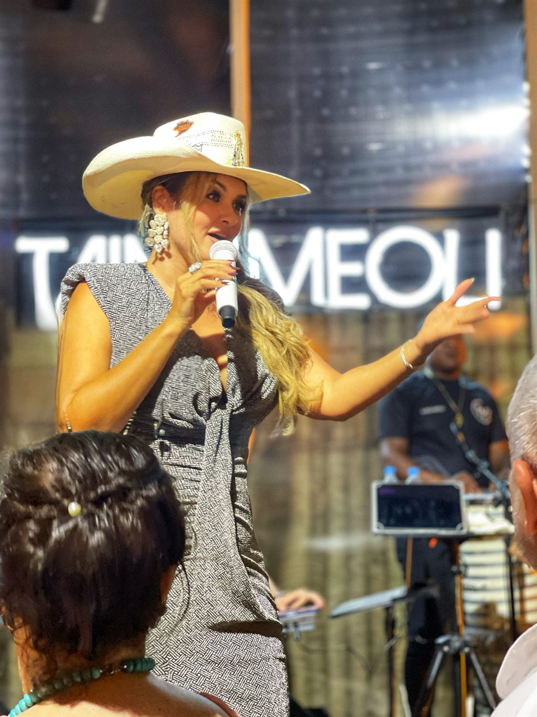 Tainá Meoli de chapéu branco em frente ao letreiro com seu nome