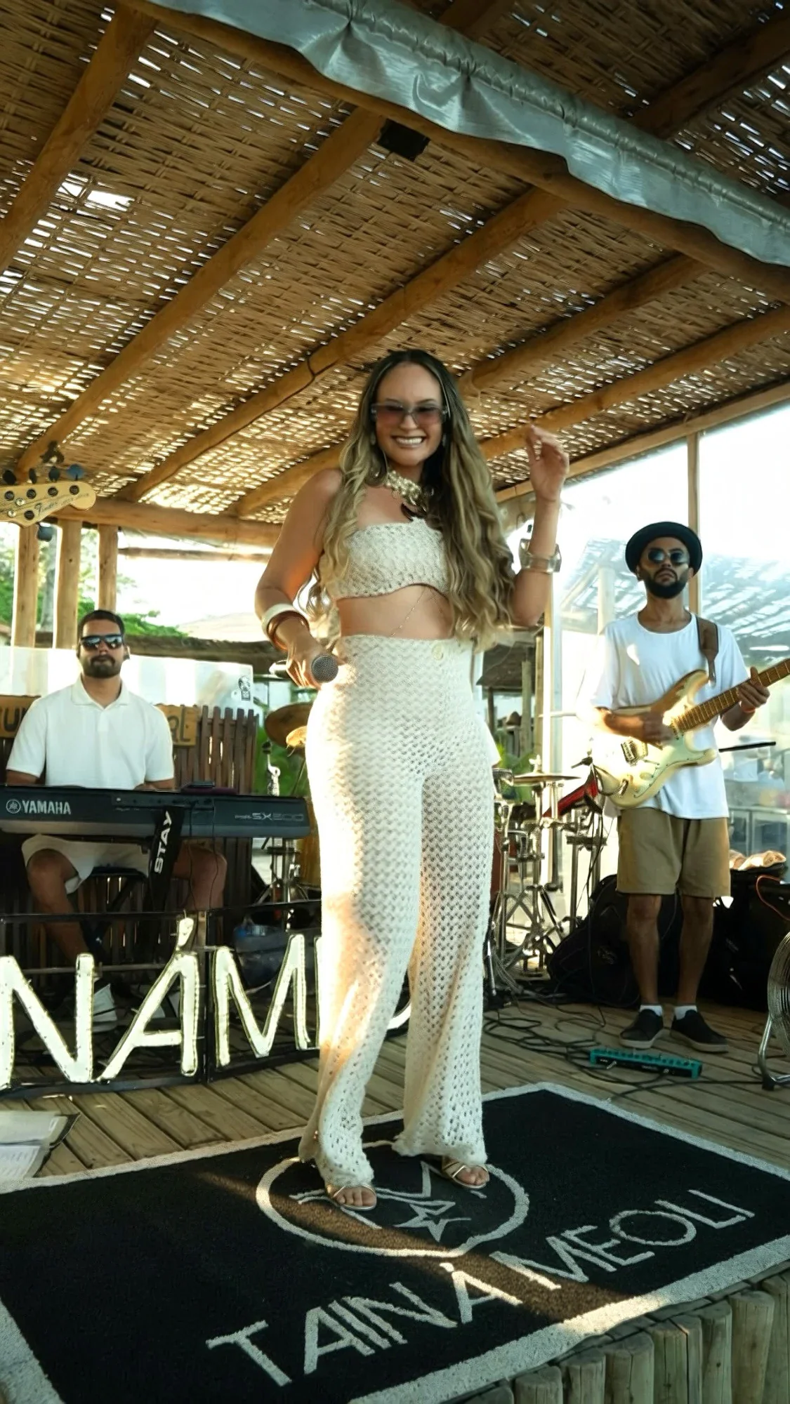 Tainá cantando com a banda em um evento durante o dia